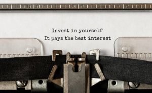 a typewriter that has a piece of paper in it that says “Invest in yourself. It pays the best interest.”